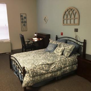 A cozy bedroom with a bed, desk, and warm decor.