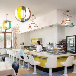 A retro-style diner interior with colorful pendant lights and counter seating.