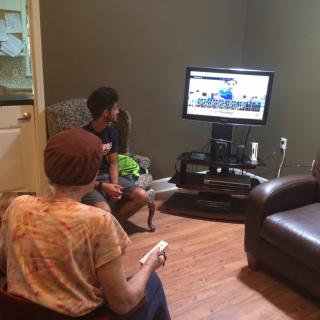 Two people playing video games in a cozy living room setup.