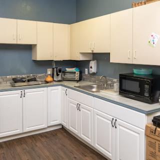 A modern kitchen featuring white cabinets, a countertop with a sink, and various appliances.