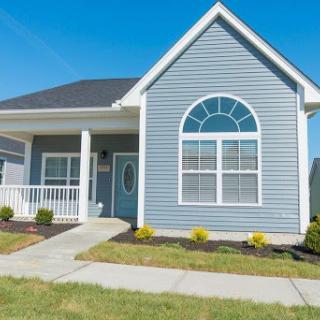 A charming blue-sided house featuring a welcoming front porch and well-maintained landscaping.