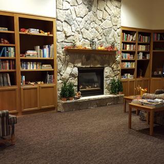 A cozy library with wooden bookshelves and a stone fireplace.