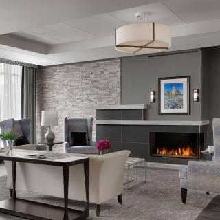 A modern living room with a cozy fireplace, elegant seating, and tasteful decor in neutral tones.