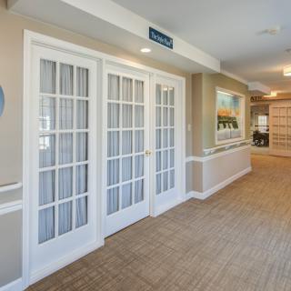 A bright hallway with French doors, wood flooring, and wall artwork.