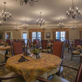 A spacious and elegantly decorated dining room with chandeliers and neatly arranged tables.