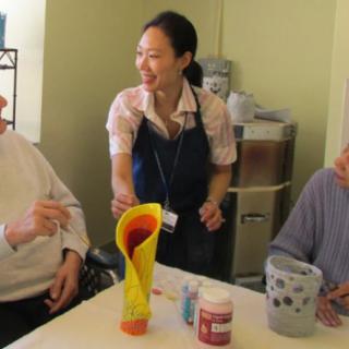 An art therapy session where an instructor engages with elderly participants in a painting activity.