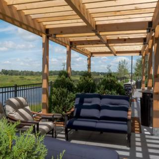 A cozy patio with a wooden pergola, comfortable seating, and a scenic view of the landscape.