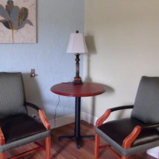A cozy seating area with two chairs and a table, adorned by a lamp and a wall painting.