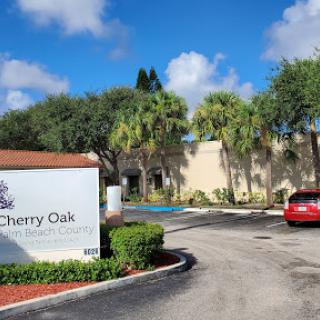 Entrance to Cherry Oak, featuring a sign and lush surroundings.