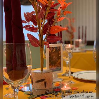 Elegant autumn-themed table setting with colorful leaves and wine glasses.