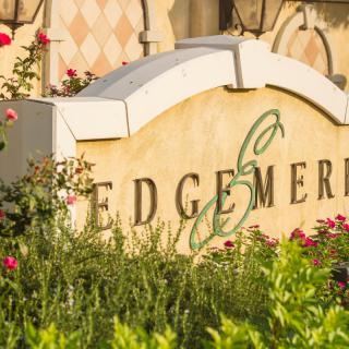 A garden sign surrounded by vibrant flowers and lush greenery.