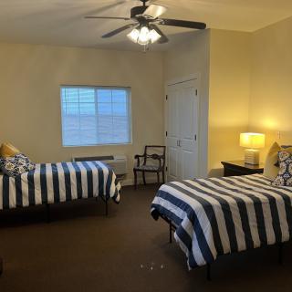 A cozy bedroom with two striped beds and a ceiling fan.