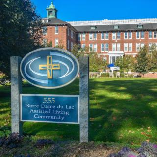 Notre Dame du Lac Alumn United University campus entrance with a visible building in the background.