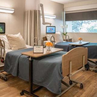 A modern hospital room with two patient beds and comfortable amenities.