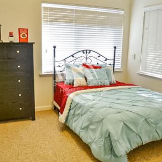 A cozy bedroom with a neatly made bed and a chest of drawers.