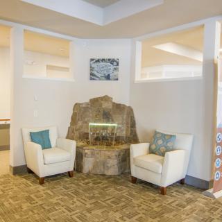 A modern waiting area with two chairs and a decorative stone fountain.
