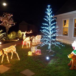 A festive outdoor Christmas display with illuminated reindeer and a glowing tree.