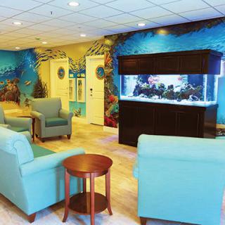 A cozy waiting room with an underwater-themed mural and a large aquarium.