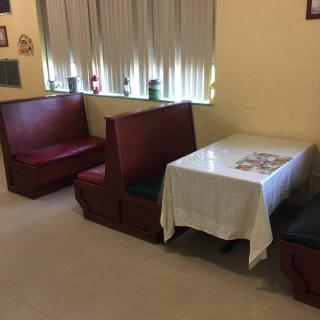 A cozy restaurant dining area with red booths and a table covered with a white tablecloth.