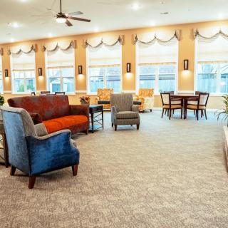 A spacious living room with comfortable seating, large windows, and warm lighting.