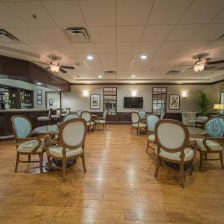 A spacious dining area featuring elegant chairs and tables, with warm lighting and hardwood floors.