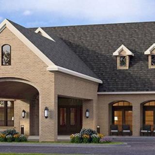 A suburban brick house with multiple windows and a peaked roof.