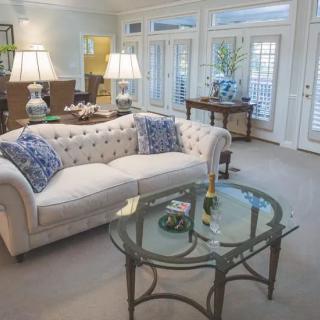 A well-lit living room featuring a stylish sofa with decorative pillows and a glass coffee table.