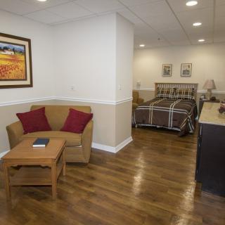 A cozy living space with a sofa and bed, featuring wooden floors and warm decor.