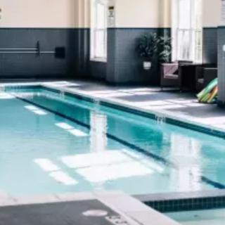 A modern indoor swimming pool area with seating and natural light.