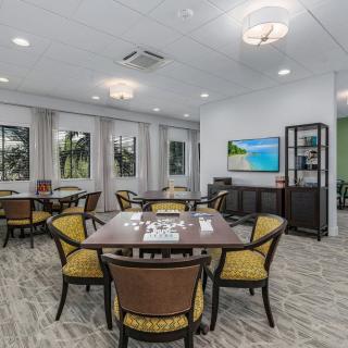 A modern dining room with multiple tables and chairs, featuring wall artwork and a television.