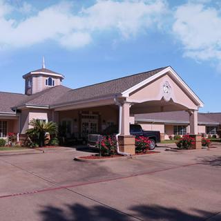 A large building with a covered entrance and driveway on a sunny day.