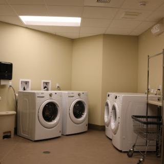 A clean and organized laundry room featuring multiple washing machines and a dryer.