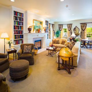 A cozy and well-decorated living room featuring comfortable seating, a fireplace, and a bookshelf.