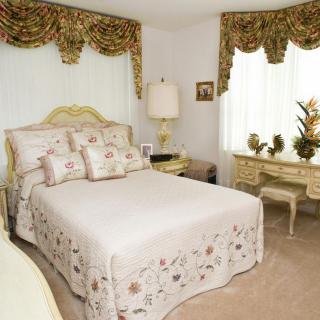 A classic bedroom with traditional decor including patterned drapes, a plush bed, and antique-style furniture.