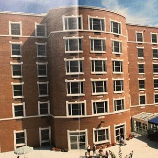 A multi-story residential building featuring a brick facade and large windows, under a clear blue sky.