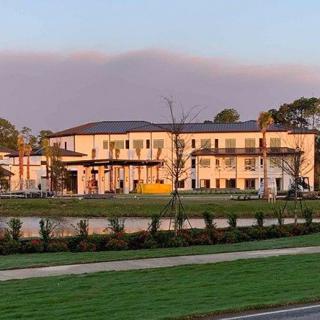 A modern hospital building surrounded by landscaped gardens at sunset.