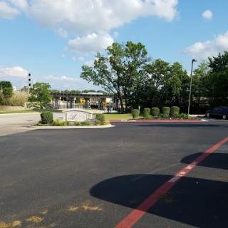 A view of a parking lot with trees and a partially cloudy sky.