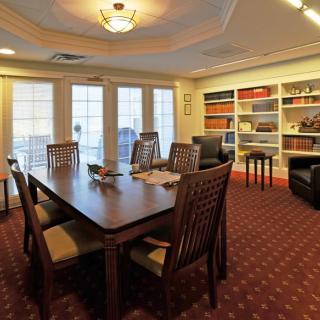 A well-furnished dining room with a large table, chairs, and bookshelves lining the walls.