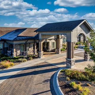 A modern residential building with a covered entrance and landscaped surroundings.