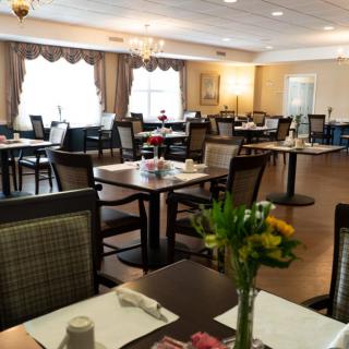 A cozy restaurant dining room with neatly arranged tables and chairs, decorated with flowers.