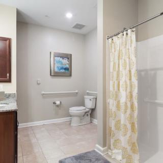 A modern bathroom featuring a shower with a patterned curtain, a toilet, and a vanity with a mirror.