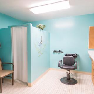 A brightly colored hair salon featuring a comfortable chair and a shower stall in a serene blue space.