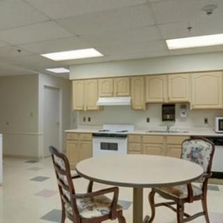 A modern kitchen with wooden cabinets, a round table, and chairs.