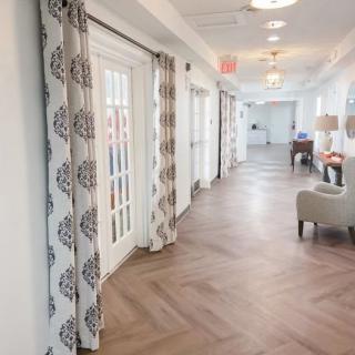 A modern, well-lit hallway with wooden flooring and decorative curtains.