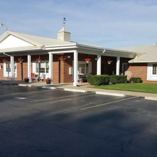 The image shows the exterior of a building with a parking lot in front, captured during the daytime.