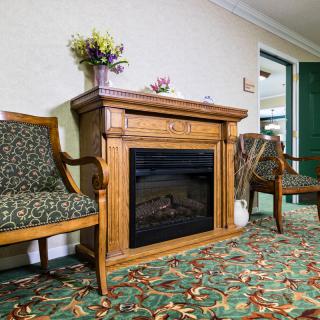 A cozy room featuring a wooden fireplace and elegant chairs on a patterned carpet.