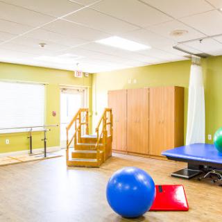 A bright and spacious physical therapy room equipped with various exercise tools and facilities.