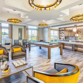 A stylish and modern lounge area featuring comfortable seating, a pool table, and a kitchen space with elegant lighting.