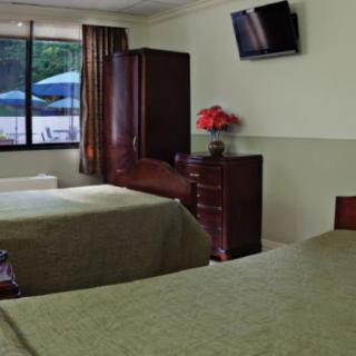 A hotel room with two beds, a flat-screen TV, and a window overlooking a patio.