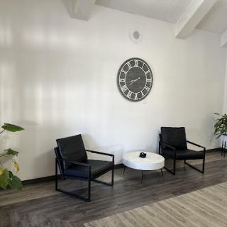 A modern waiting area featuring black chairs, a round coffee table, and decorative plants.